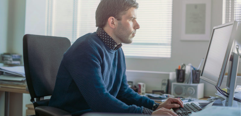 Male professional using computer in brightly lit office